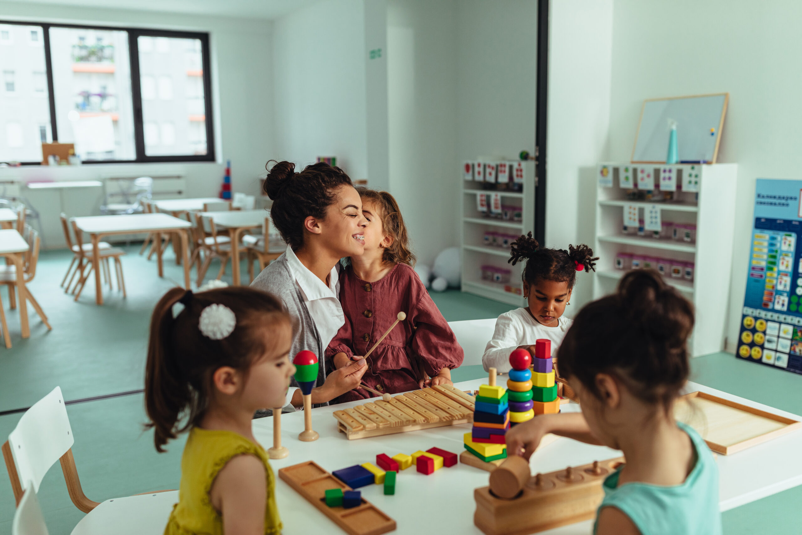 A teacher with four children at a table.