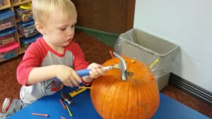 child-hammering-pumpkin