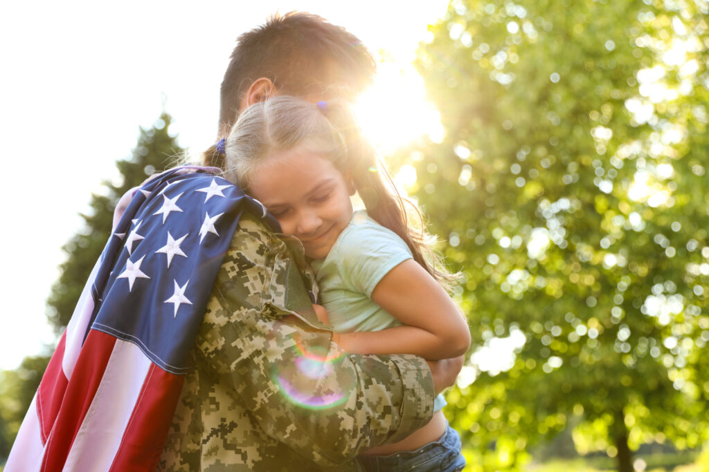 Father in military uniform with American flag holding his little