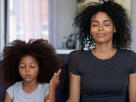 Child and adult seated on couch, meditative and relaxed