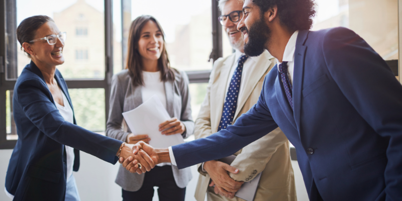 Group of professionals in standing and two people shaking hands