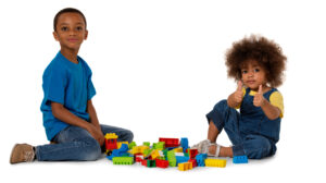 Two little cute African American children playing on the floor with lots of colorful plastic blocks in studio, isolated on white background