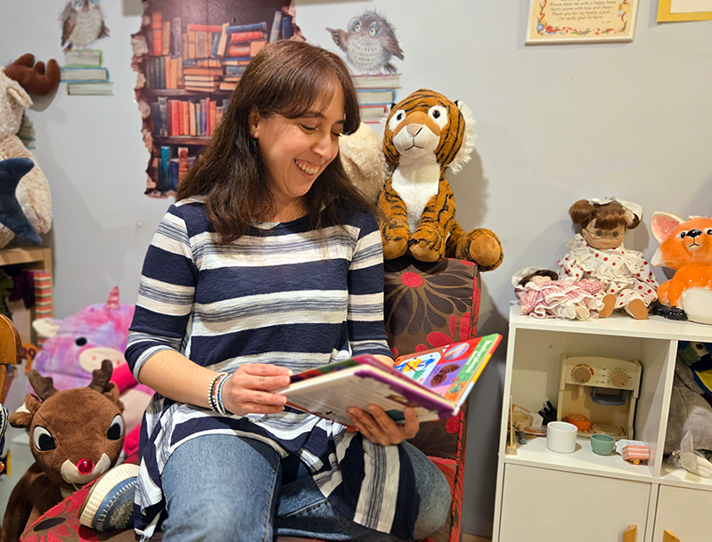 Family child care provider reading children's book in early learning setting.
